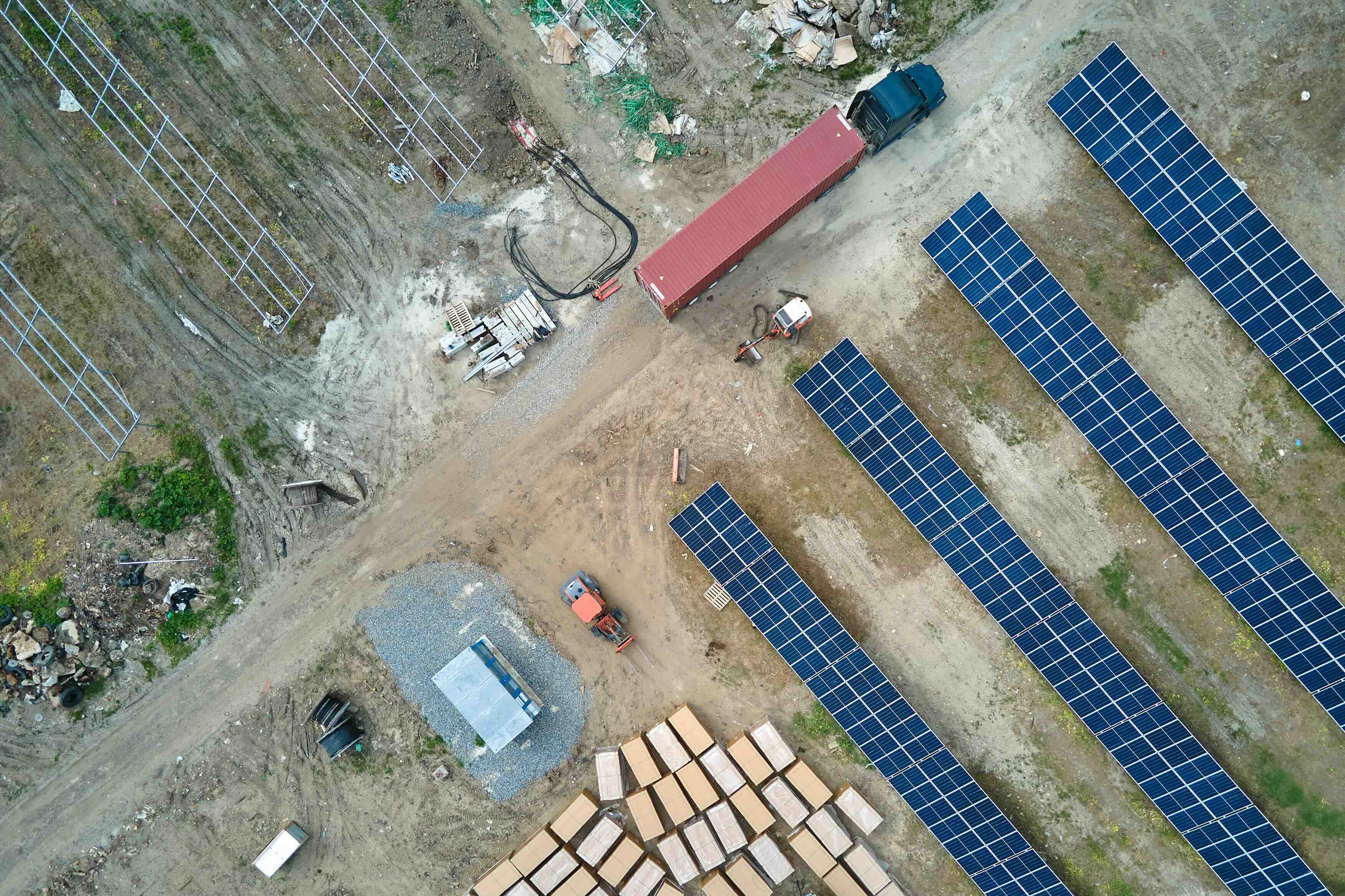 aerial view of solar farm construction site in progress with trucks and scattered materials 