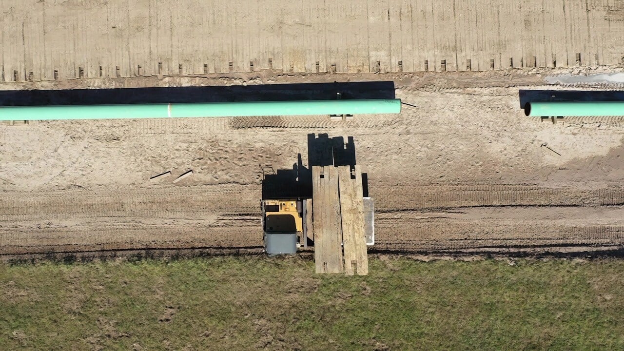 Aerial view of temporary ground protection mats laid out at a construction site with heavy machinery operating on them.